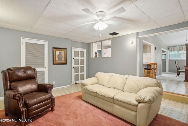 tiled living room featuring a drop ceiling and ceiling fan