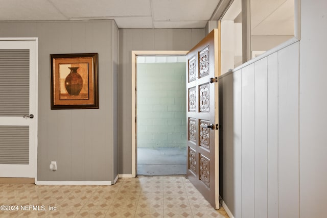 hallway with wood walls and a drop ceiling