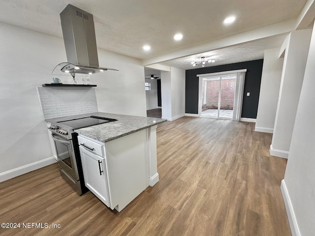 kitchen featuring light stone countertops, light wood-type flooring, stainless steel range with electric stovetop, island range hood, and white cabinetry