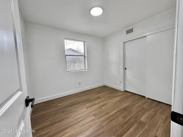 unfurnished bedroom with dark hardwood / wood-style floors and a closet