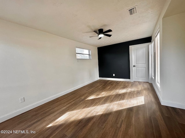 unfurnished room featuring ceiling fan, dark wood-type flooring, and a textured ceiling