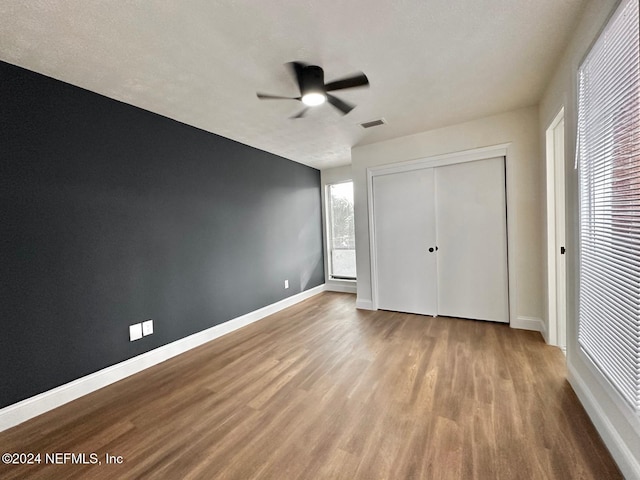 unfurnished bedroom featuring a textured ceiling, a closet, light hardwood / wood-style flooring, and ceiling fan