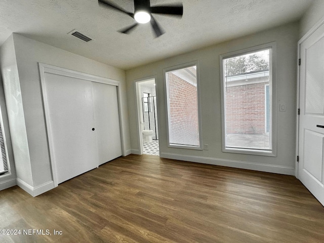 unfurnished bedroom with ensuite bath, a textured ceiling, ceiling fan, hardwood / wood-style floors, and a closet