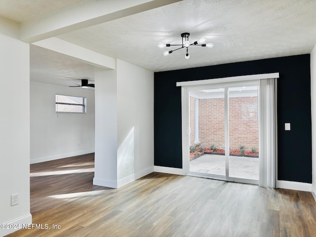 spare room featuring a chandelier, a textured ceiling, and hardwood / wood-style flooring