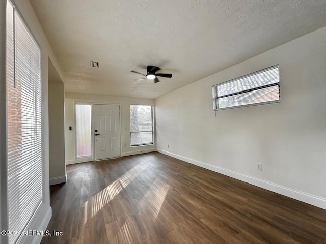 empty room with a textured ceiling, ceiling fan, and dark wood-type flooring