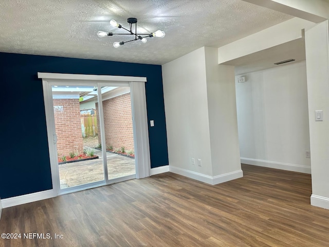 empty room featuring hardwood / wood-style floors, a textured ceiling, and an inviting chandelier