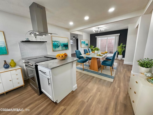 kitchen with decorative backsplash, island range hood, electric range, light hardwood / wood-style flooring, and white cabinets