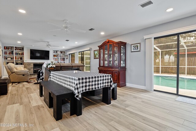 dining area featuring a fireplace, light hardwood / wood-style floors, and ceiling fan