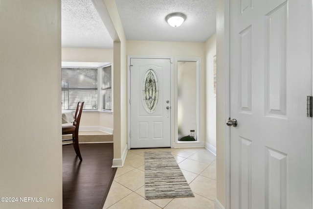 entryway with a textured ceiling and light tile patterned flooring