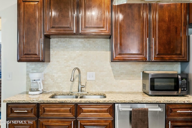 kitchen with sink, light stone countertops, stainless steel appliances, and tasteful backsplash