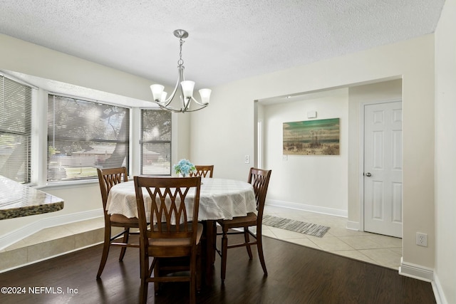 dining space with a chandelier, hardwood / wood-style floors, and a textured ceiling