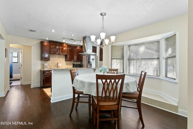 dining room featuring a chandelier, dark hardwood / wood-style flooring, a healthy amount of sunlight, and a textured ceiling