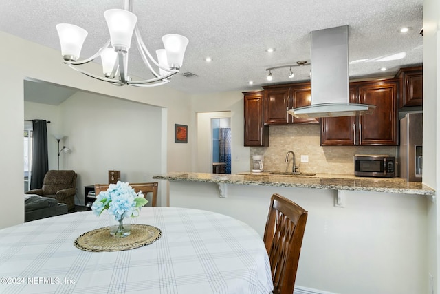 dining area with a textured ceiling, a notable chandelier, and sink