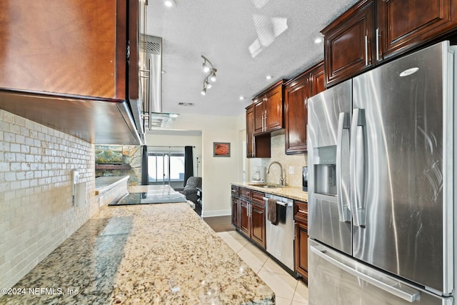 kitchen with light stone counters, a textured ceiling, stainless steel appliances, sink, and light tile patterned floors