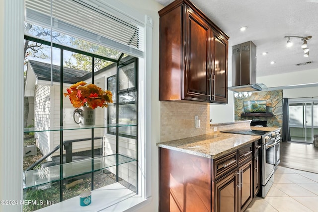 kitchen featuring a textured ceiling, stainless steel electric range oven, backsplash, and wall chimney range hood