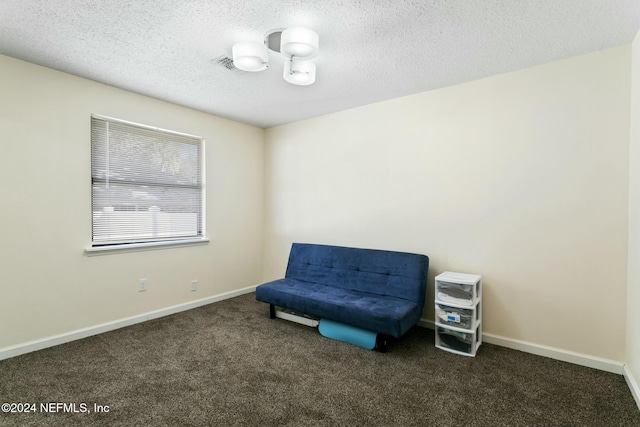 living area with a textured ceiling and dark carpet