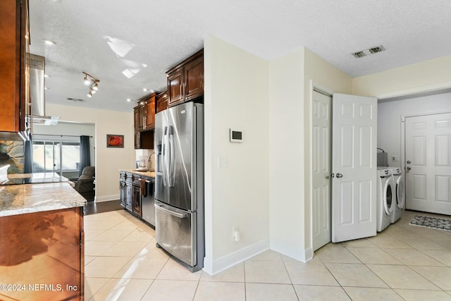 kitchen with sink, washer and dryer, a textured ceiling, range hood, and stainless steel appliances