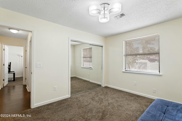 bedroom featuring dark carpet, a textured ceiling, and a closet