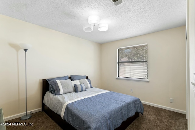 bedroom featuring a textured ceiling and dark carpet