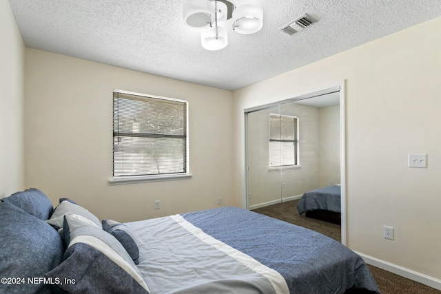 carpeted bedroom with a closet and a textured ceiling