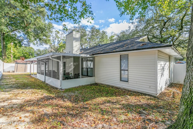 back of house featuring a sunroom, a yard, and a storage shed