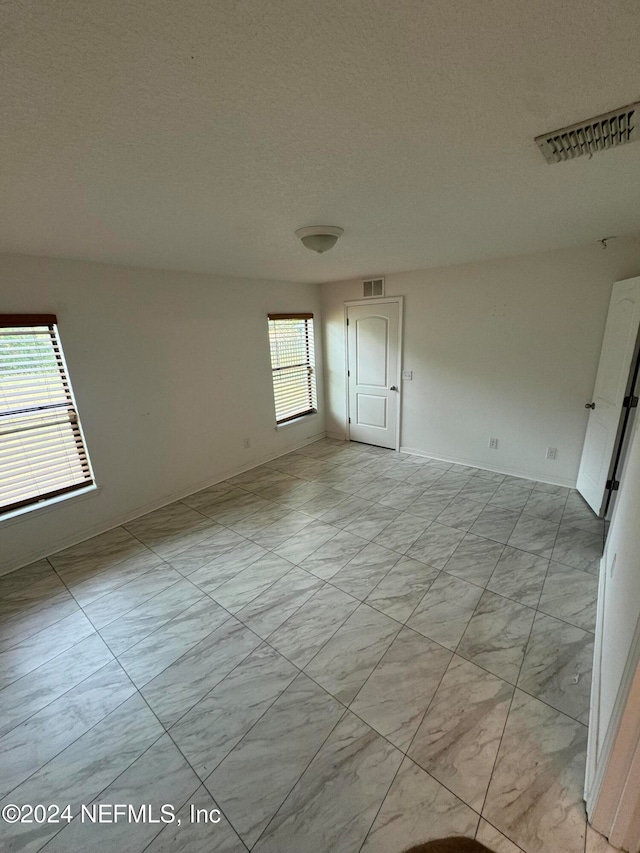 unfurnished room featuring a textured ceiling