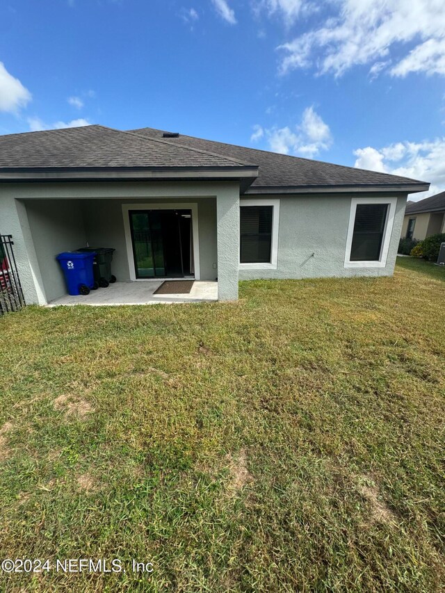 back of house featuring a lawn and a patio area