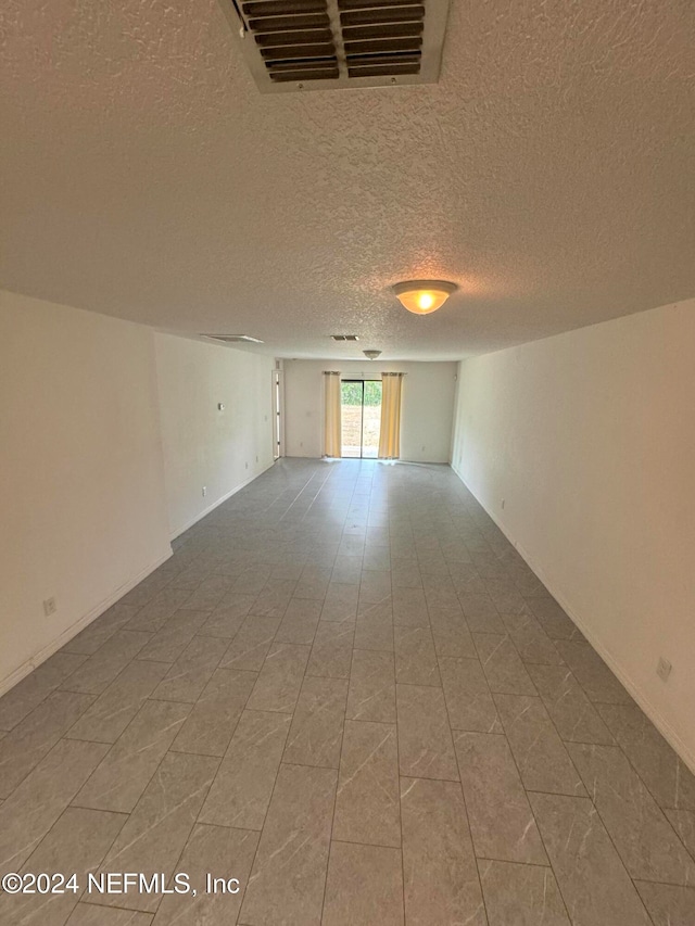 spare room with tile patterned flooring and a textured ceiling