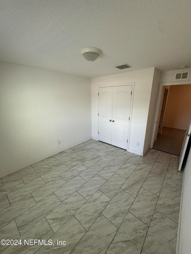 unfurnished bedroom with a textured ceiling and a closet