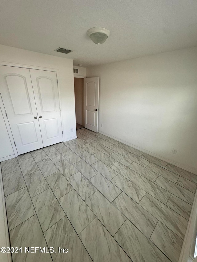 unfurnished bedroom with a closet and a textured ceiling