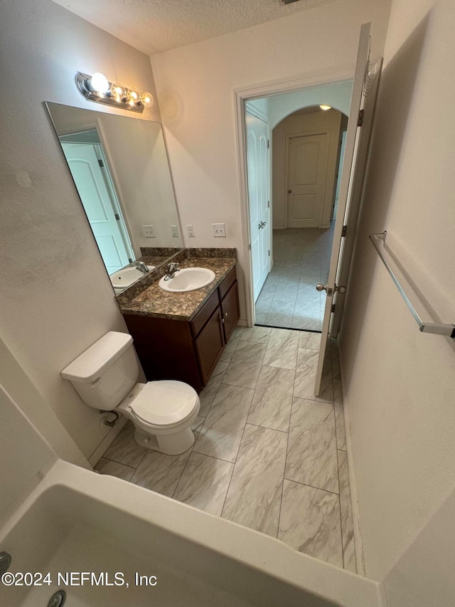 bathroom featuring vanity, a textured ceiling, and toilet