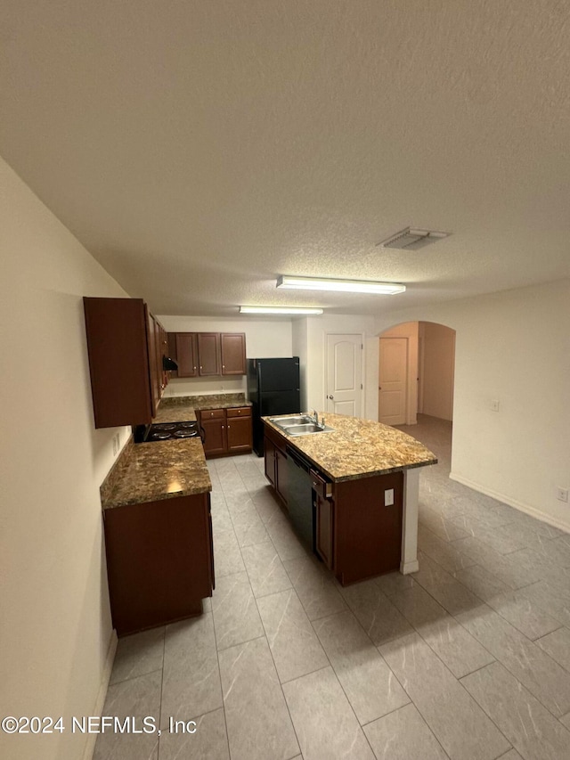 kitchen featuring black appliances, a textured ceiling, sink, an island with sink, and light tile patterned flooring