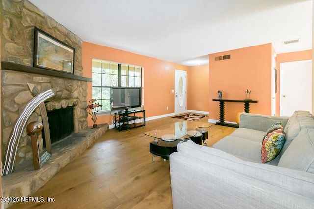 living room with wood-type flooring and a stone fireplace