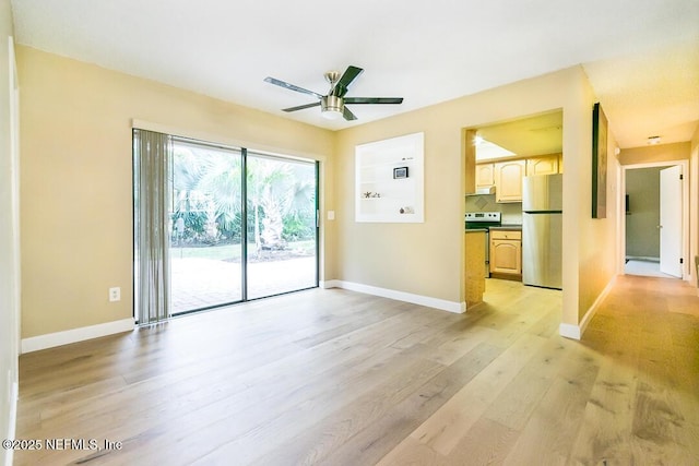 interior space featuring ceiling fan, light wood-style flooring, and baseboards