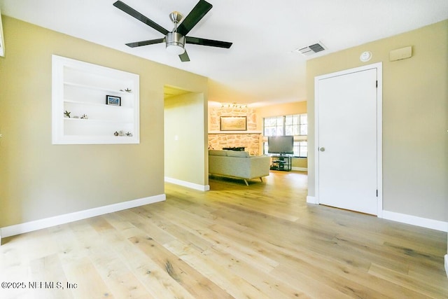 unfurnished room with built in shelves, baseboards, visible vents, and light wood finished floors