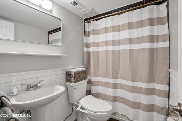 bathroom featuring sink, a shower with shower curtain, and toilet