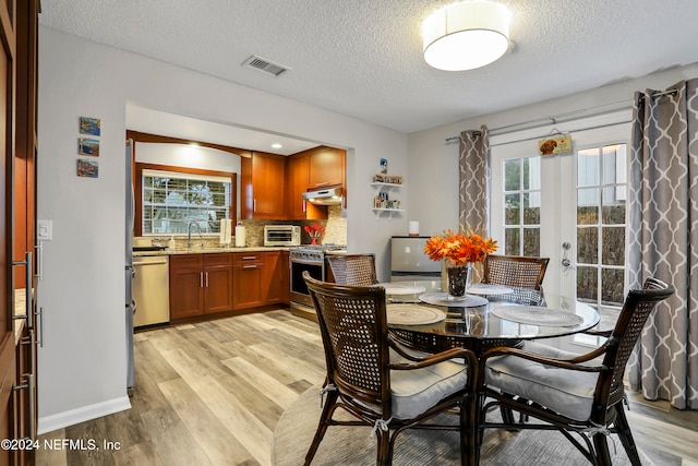 dining area with a textured ceiling, light hardwood / wood-style floors, a healthy amount of sunlight, and sink