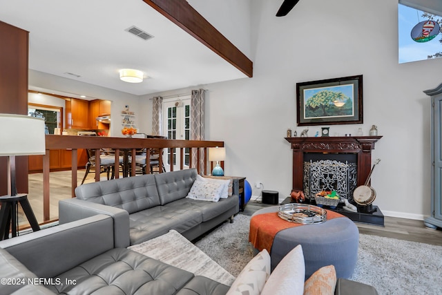 living room featuring light hardwood / wood-style floors, a premium fireplace, and beam ceiling