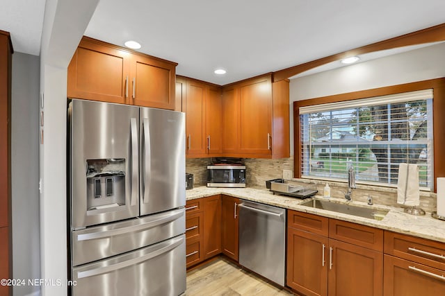 kitchen with sink, light stone countertops, stainless steel appliances, and tasteful backsplash