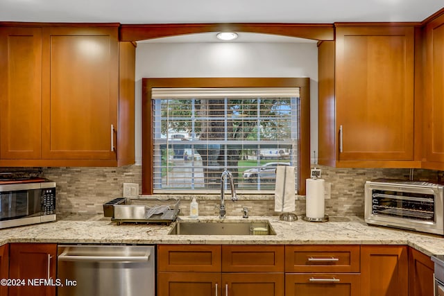 kitchen with decorative backsplash, stainless steel appliances, light stone counters, and sink