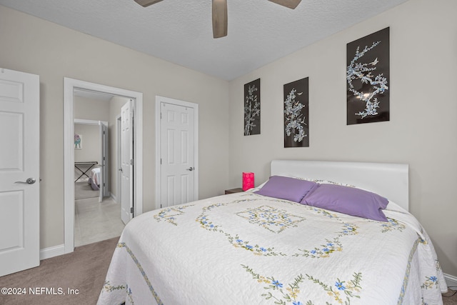 carpeted bedroom with ceiling fan and a textured ceiling