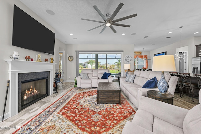 living room featuring a textured ceiling, light hardwood / wood-style floors, and ceiling fan