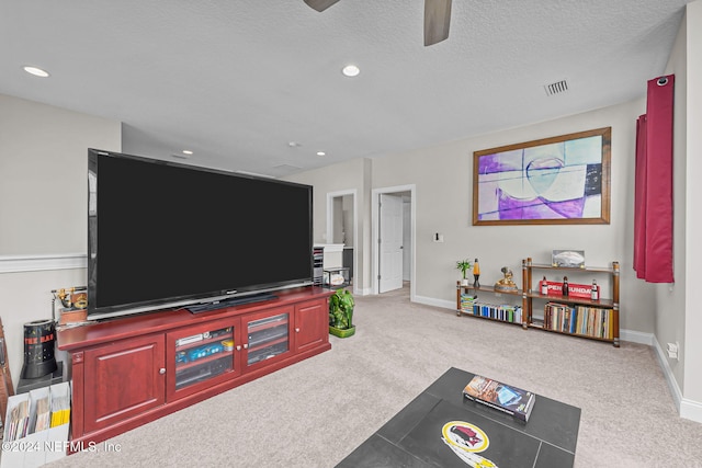 living room with light carpet, ceiling fan, and a textured ceiling