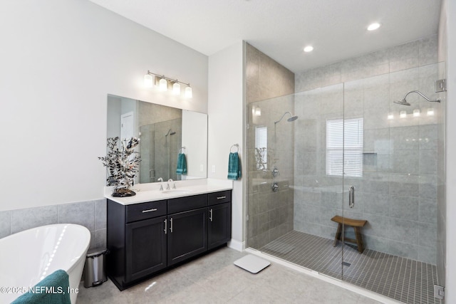 bathroom with tile patterned flooring, a stall shower, a freestanding tub, vanity, and recessed lighting