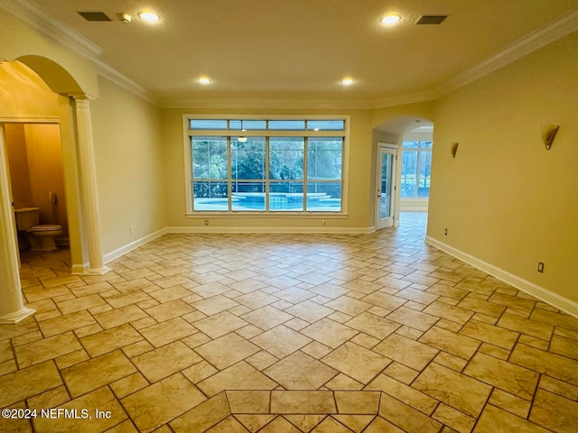 empty room featuring decorative columns and crown molding