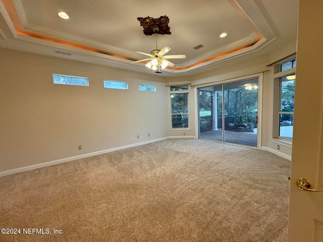 carpeted spare room with a raised ceiling, ceiling fan, and crown molding