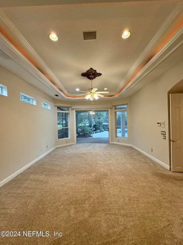 unfurnished living room with a tray ceiling, ceiling fan, carpet flooring, and ornamental molding