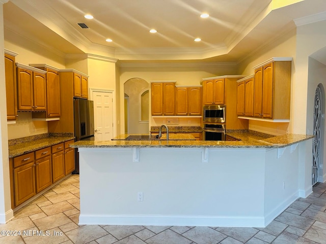 kitchen with a breakfast bar, crown molding, dark stone countertops, appliances with stainless steel finishes, and kitchen peninsula