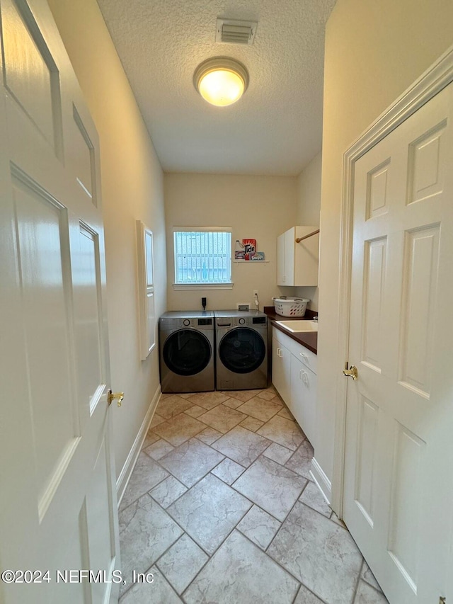 laundry room with cabinets, washer and dryer, and a textured ceiling