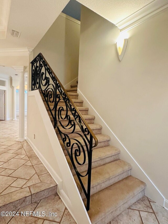 staircase featuring a textured ceiling and crown molding